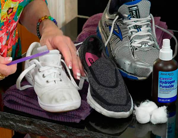 На изображении руки немолодой женщины в процессе обработке обуви от грибка